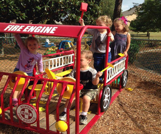 Children playing on red playground fire engine