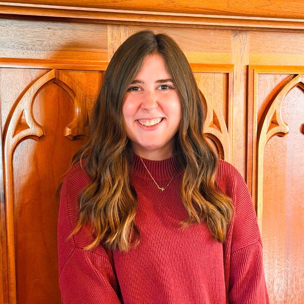 Smiling woman in red sweater by wooden panel