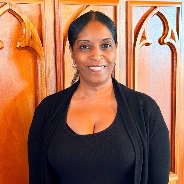 Smiling woman wearing black top by carved wood